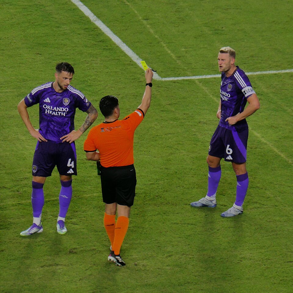 Árbitro mostrando tarjeta amarilla a un jugador